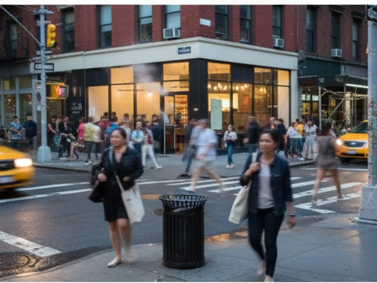 Twilight street-level view of a busy NYC block with a modern, softly lit pizza restaurant on the corner, pedestrians in casual summer clothes passing by, yellow cabs in motion, and steam rising from sidewalk grates, captured with shallow depth of field and realistic lighting.