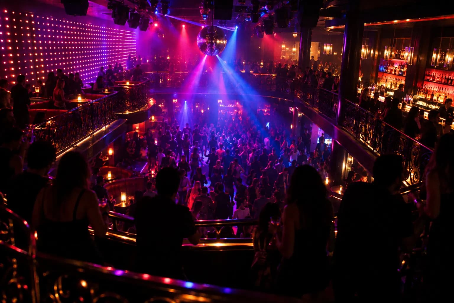 A dark club interior with a lowered dance floor and coloured light