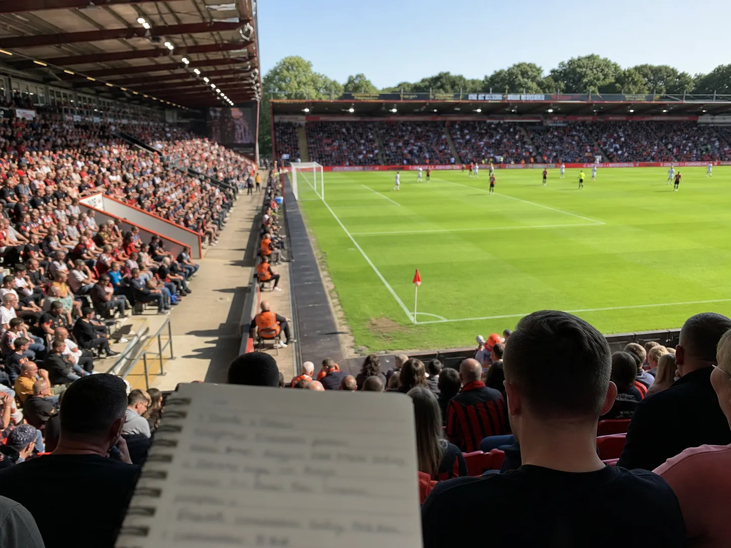 Bright realistic Bournemouth stadium interior image with transfer-watch notebook mood