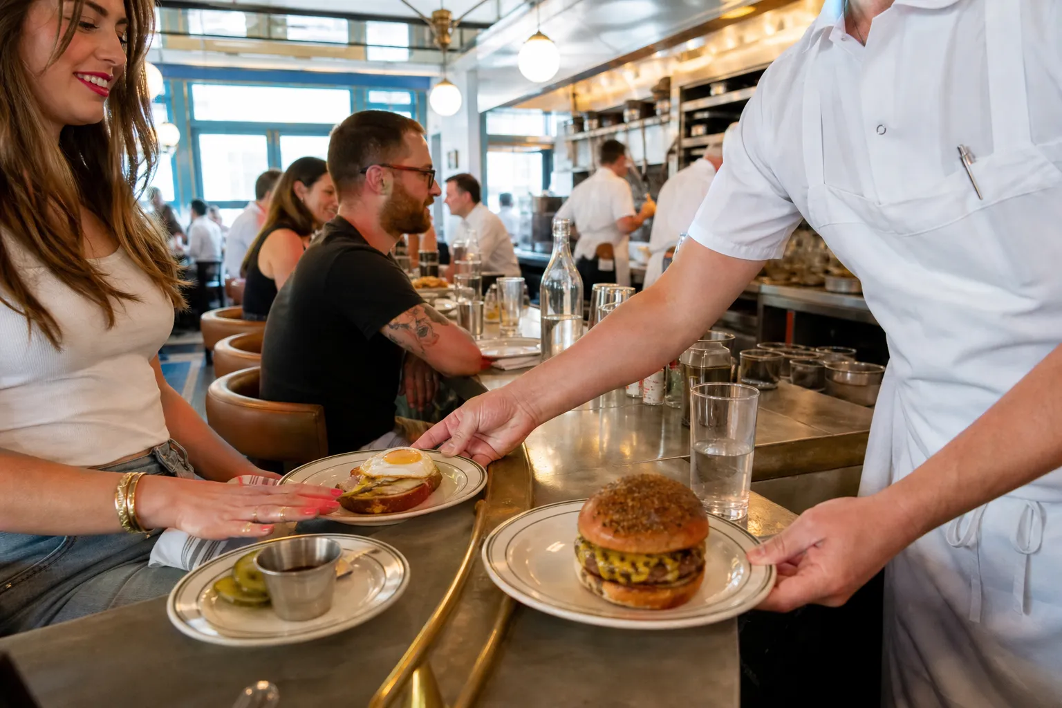 A bright NYC restaurant bar scene with plates being served for an Au Cheval planning guide