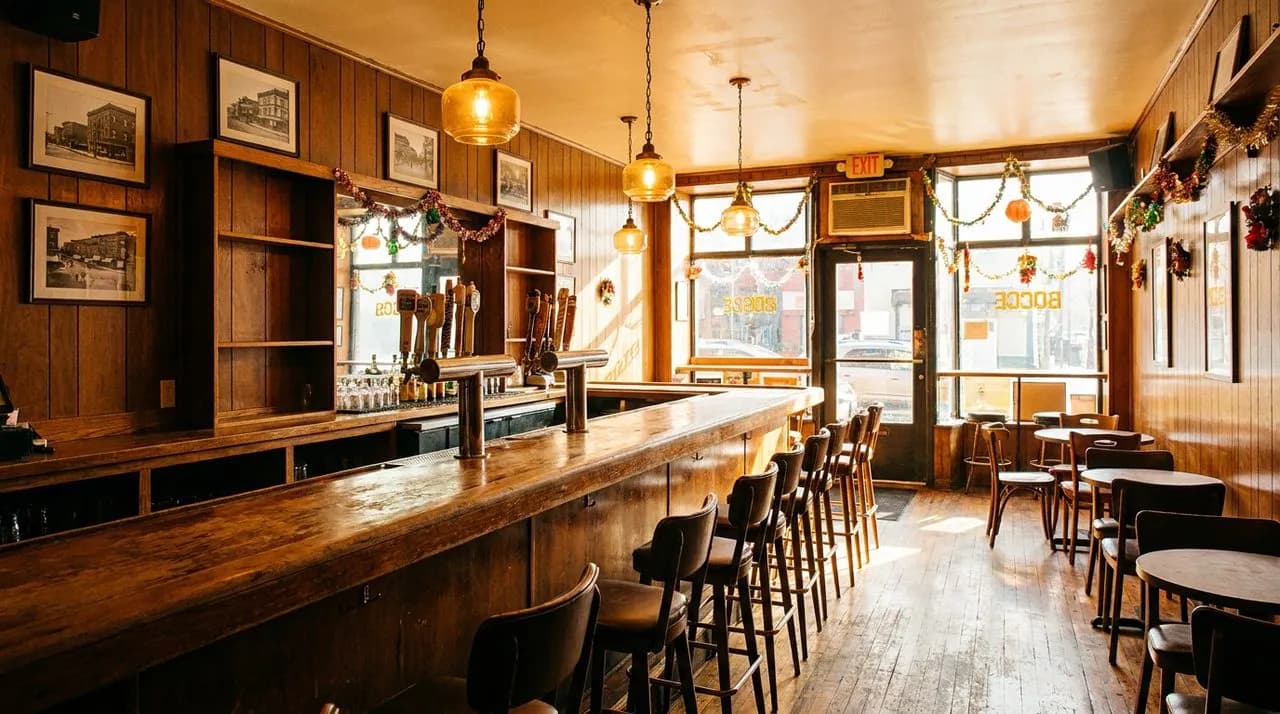 Greenpoint Polish-American bar interior on bright afternoon with warm wooden bar, vintage glass pendant lights, retro wood paneling, and golden light.