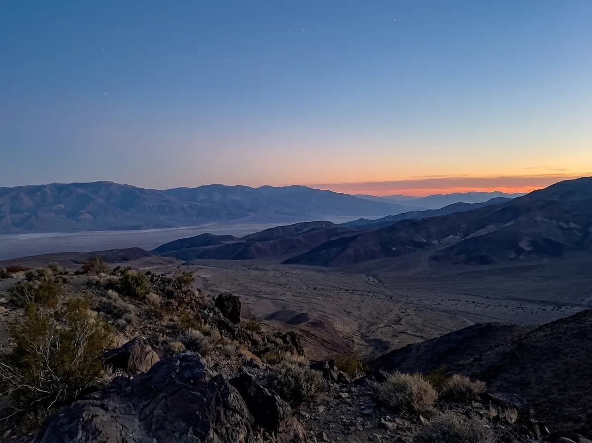 A wide desert valley seen from an elevated viewpoint, ridges layered into the distance and a basin floor below