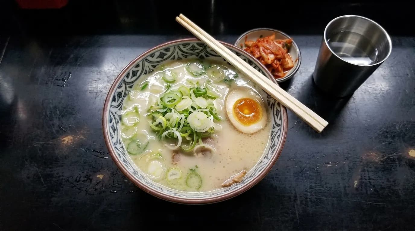 A bowl of noodle soup on a counter under fluorescent light