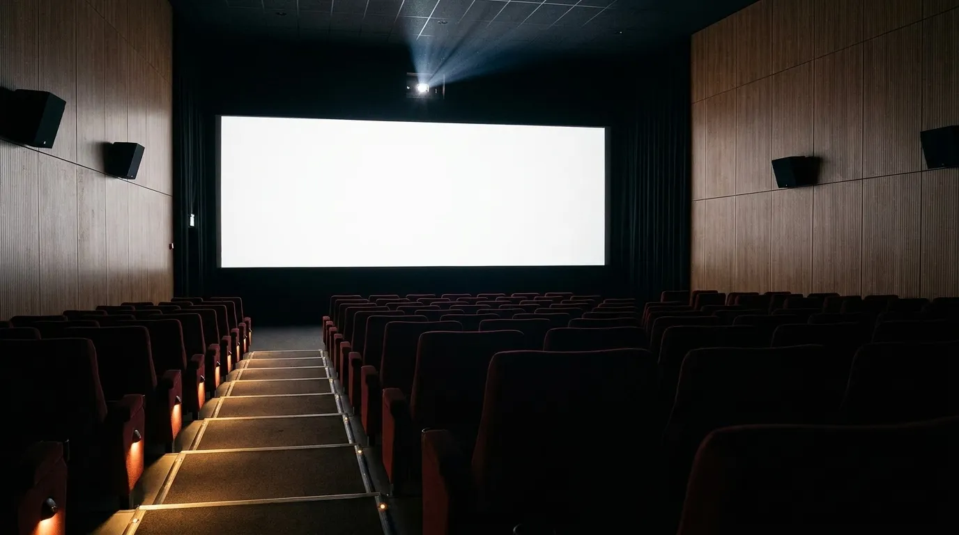 An empty cinema auditorium with rows of seats facing a blank screen