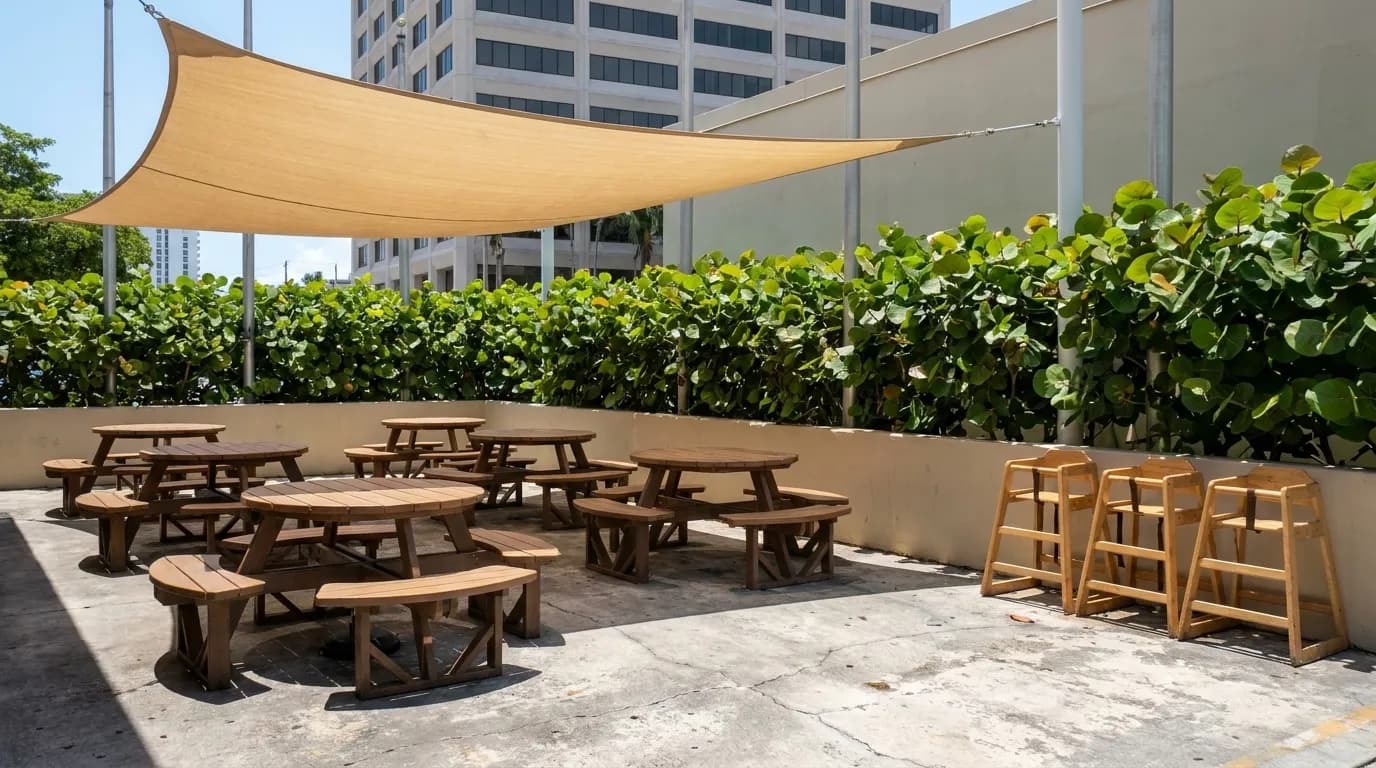 A casual restaurant patio with wooden tables under a shade sail