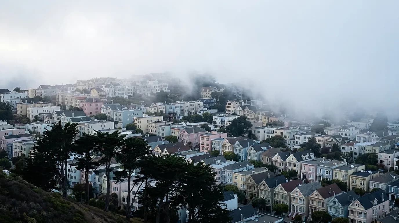 Fog pouring over a San Francisco ridge above rows of houses