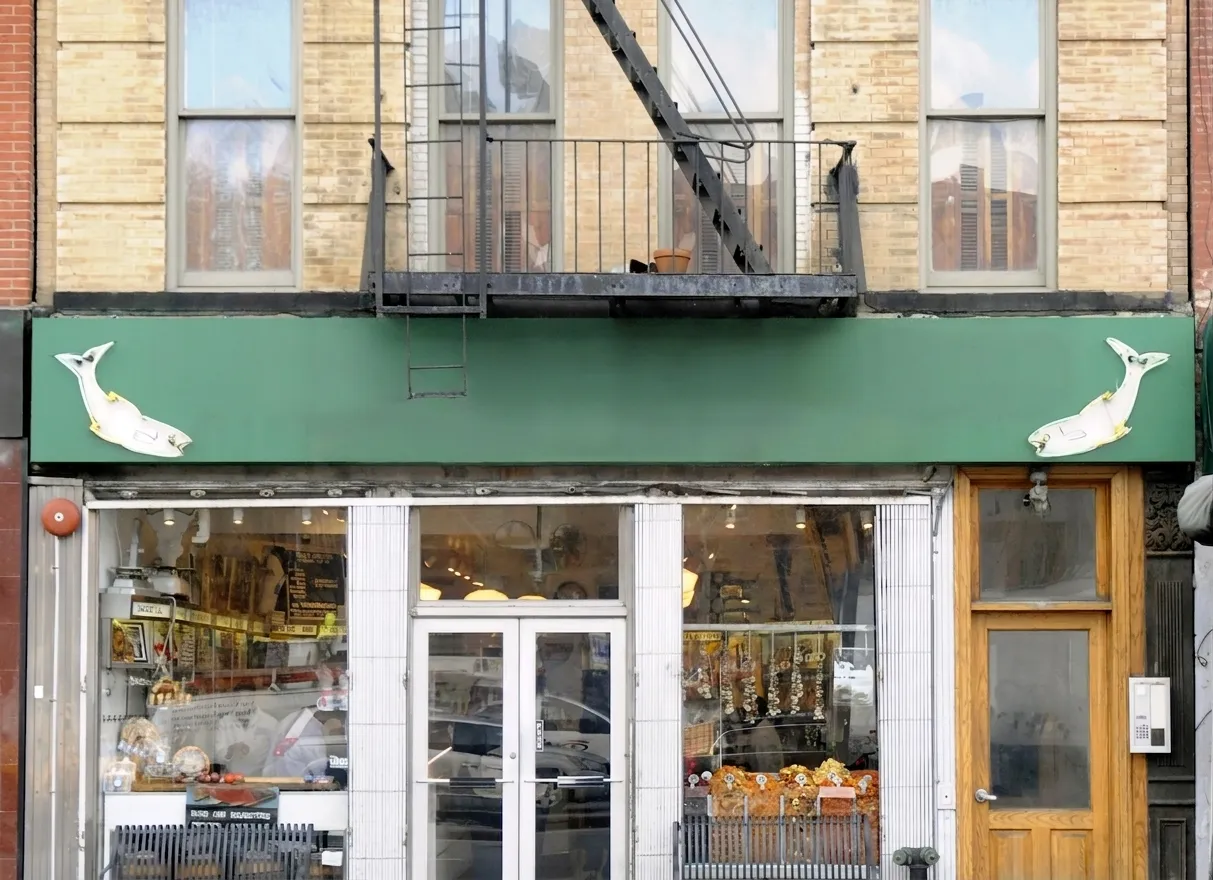 Historic Lower East Side appetizing shop storefront with a green sign band, chrome shopfront and brick tenement facade in morning light