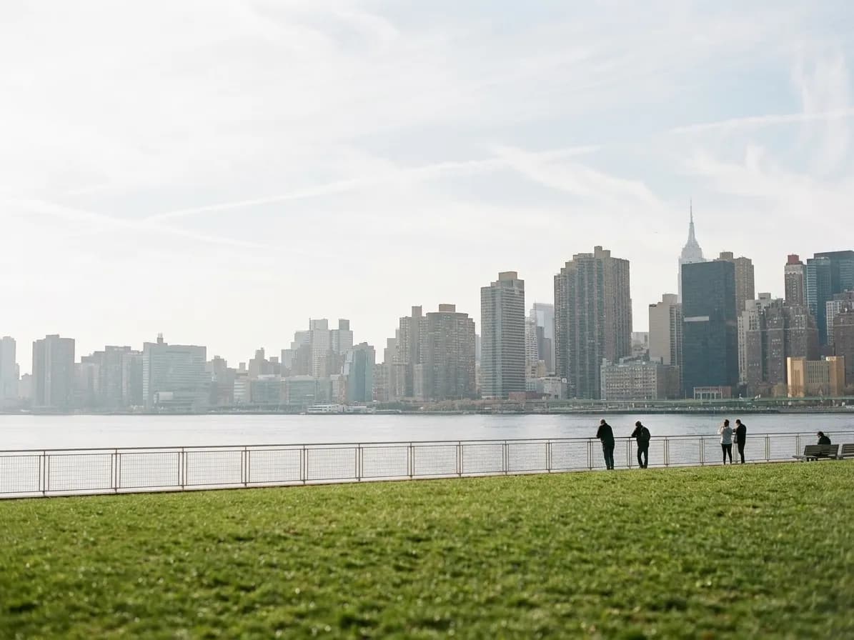 A Brooklyn waterfront park with the Manhattan skyline across the water on a clear afternoon