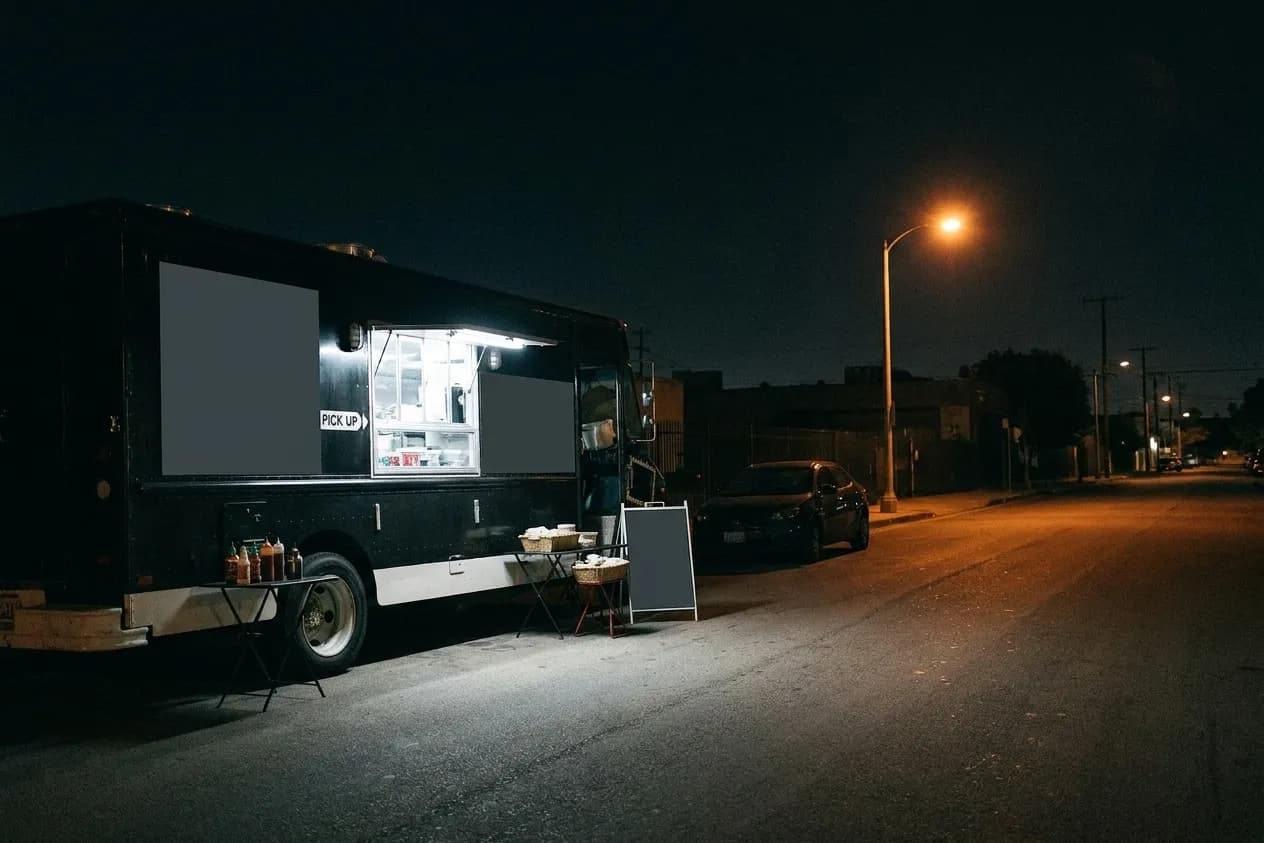 A taco truck lit from inside parked on an empty street at night
