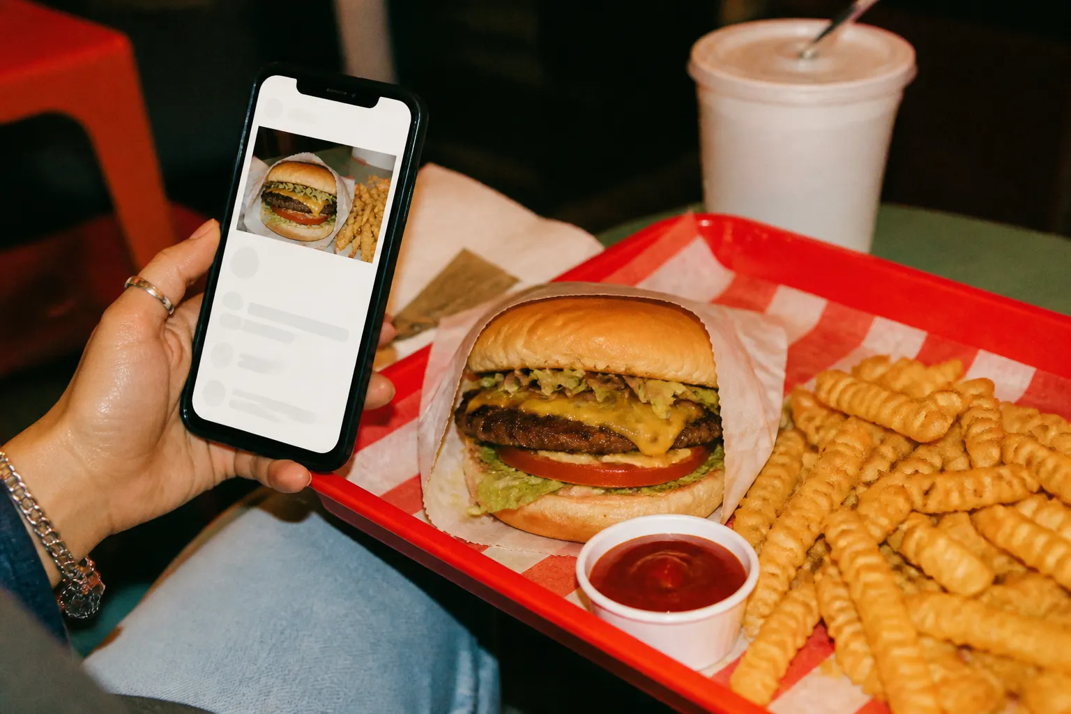 A phone screen showing a food order held next to a tray of food on a counter