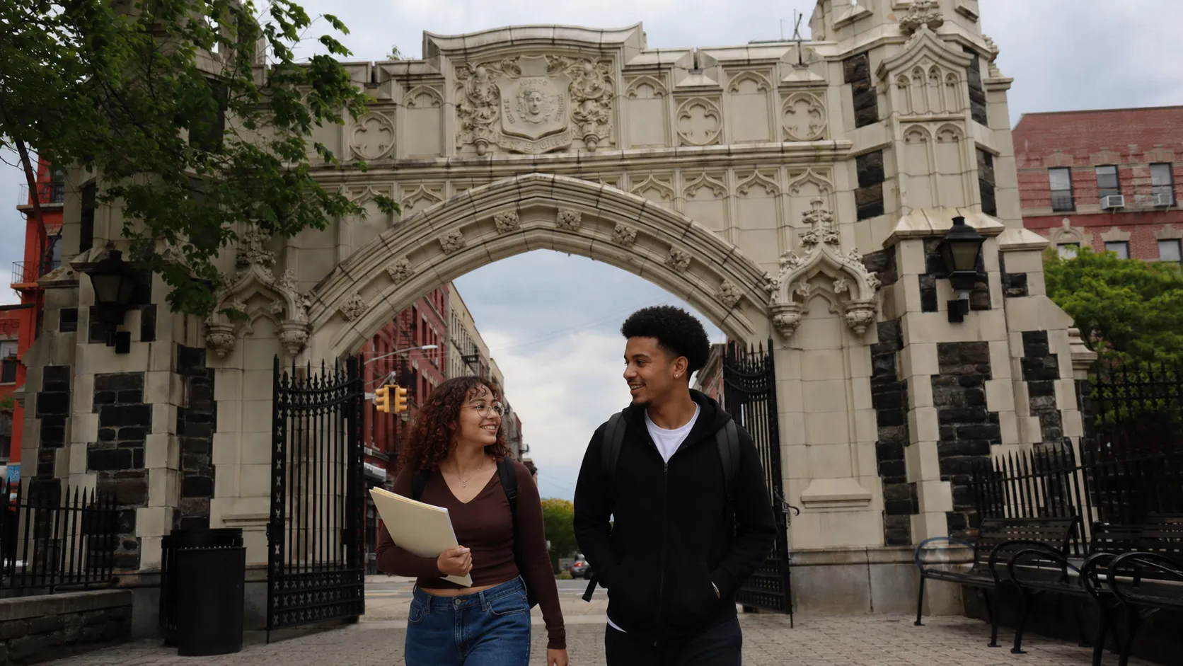 Two New York college students walking through a historic City College campus gate
