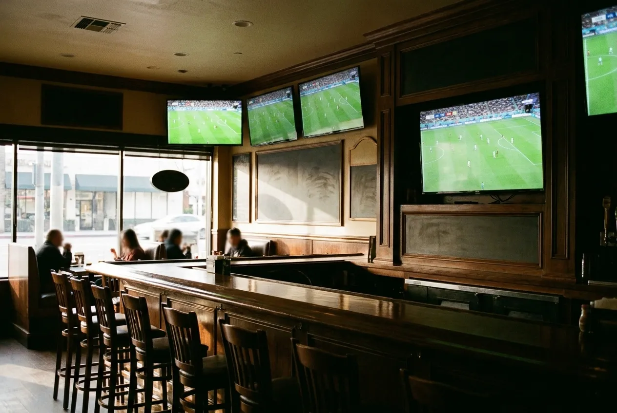 A dark wood sports bar in the morning with a live football match playing on the screens above the counter