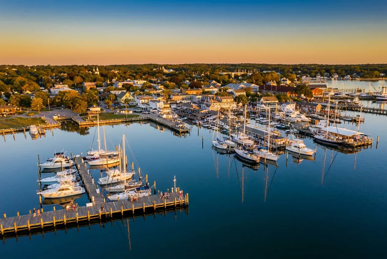 A small maritime village harbor with docked sailboats and a marina at golden hour
