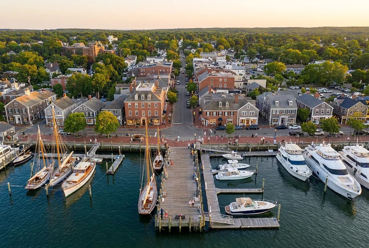 A historic whaling-village waterfront street with a wharf and boats on a warm summer evening