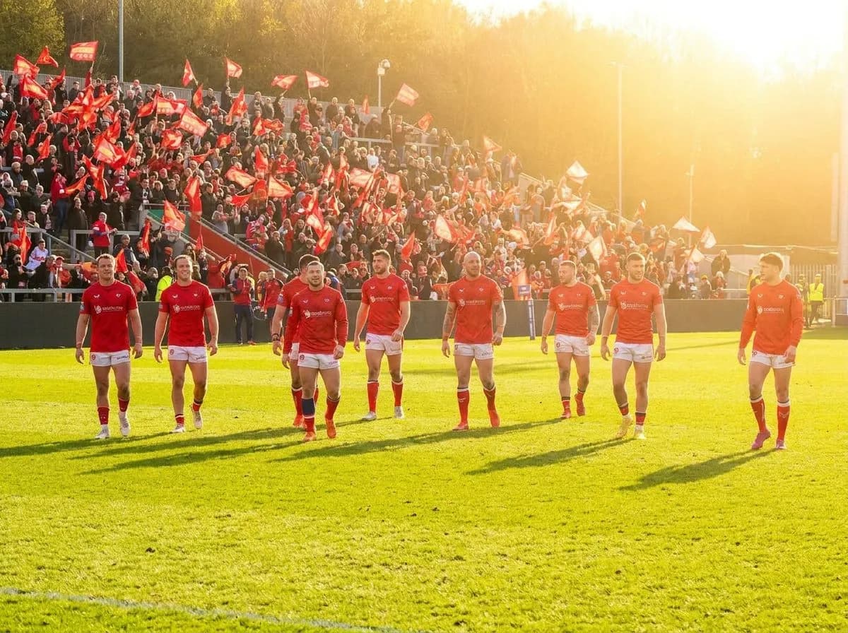 A wide sunlit pitch showing players spread across the field under clear skies, with vibrant team colors and a festive World Cup atmosphere, emphasizing space and tactical positioning in bright daylight.