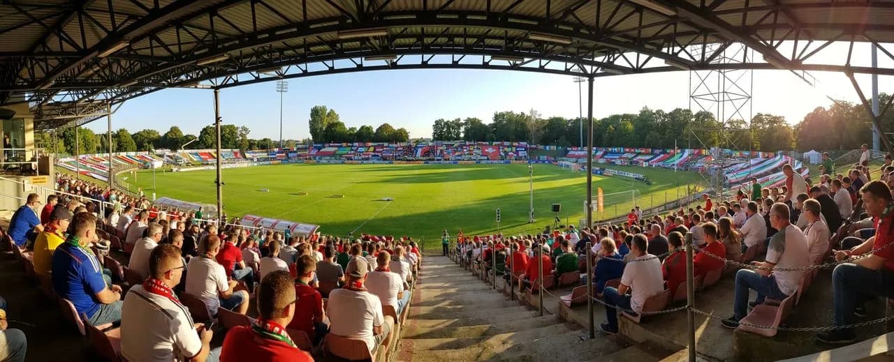 A bright stadium pitch panorama under clear light with vivid World Cup atmosphere and colorful supporter accents