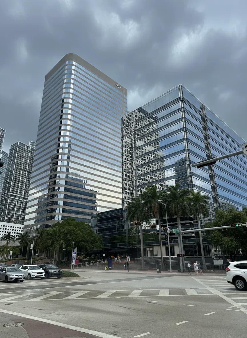 Brickell Avenue in Miami on a September afternoon, glass towers under a building storm and wet asphalt reflecting the palms