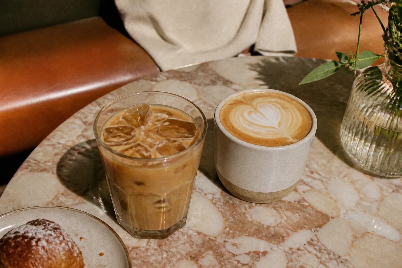 An iced coffee and a hot latte sitting side by side on a table