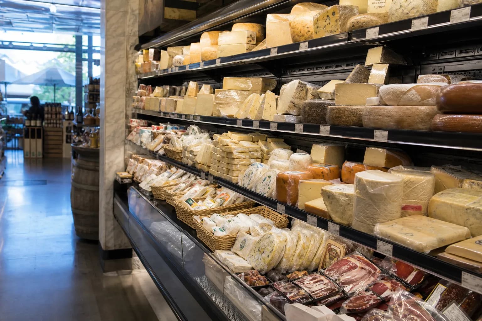 An organized display of cheese and charcuterie inside a clean grocery store aisle.