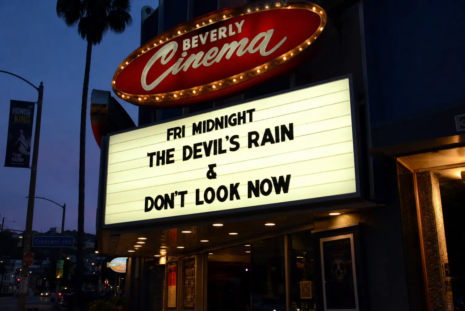 The retro neon sign and marquee of the New Beverly Cinema in Los Angeles at sunset.