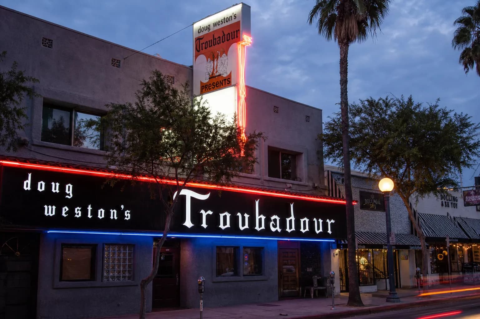 The iconic neon-lit storefront facade of the historic Troubadour music venue on Santa Monica Boulevard in West Hollywood at dusk.