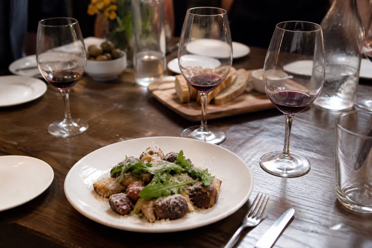 A close-up of a multi-course wine pairing dinner at Bacchus Kitchen, featuring elegant stemware and gourmet plates.
