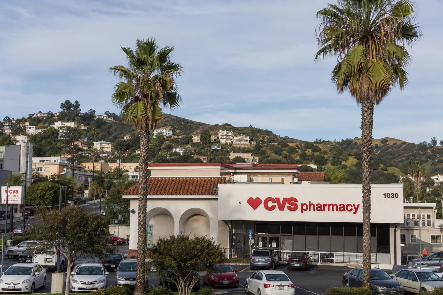 Exterior of the CVS storefront on Sunset Boulevard showing the surface parking lot and palm trees.