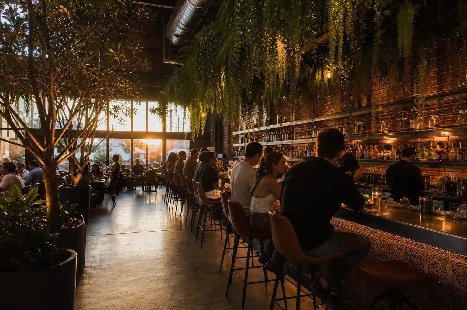 Wide shot of a bustling open-air restaurant patio in Los Angeles under hanging green plants and warm string lights at dusk