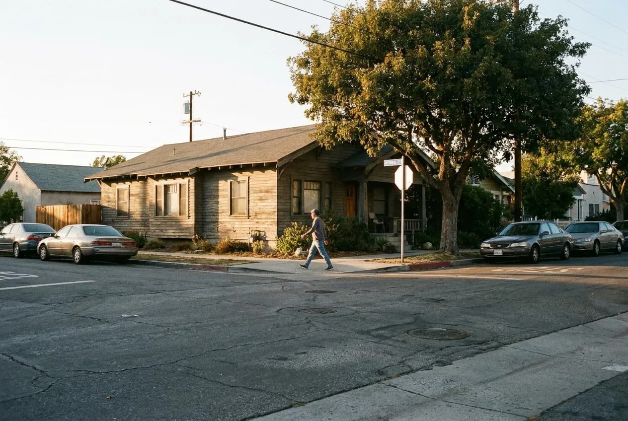 Afternoon street view of a craftsman bungalow on Virgil Avenue with a pedestrian crossing Marathon Street and parked cars along the curb.