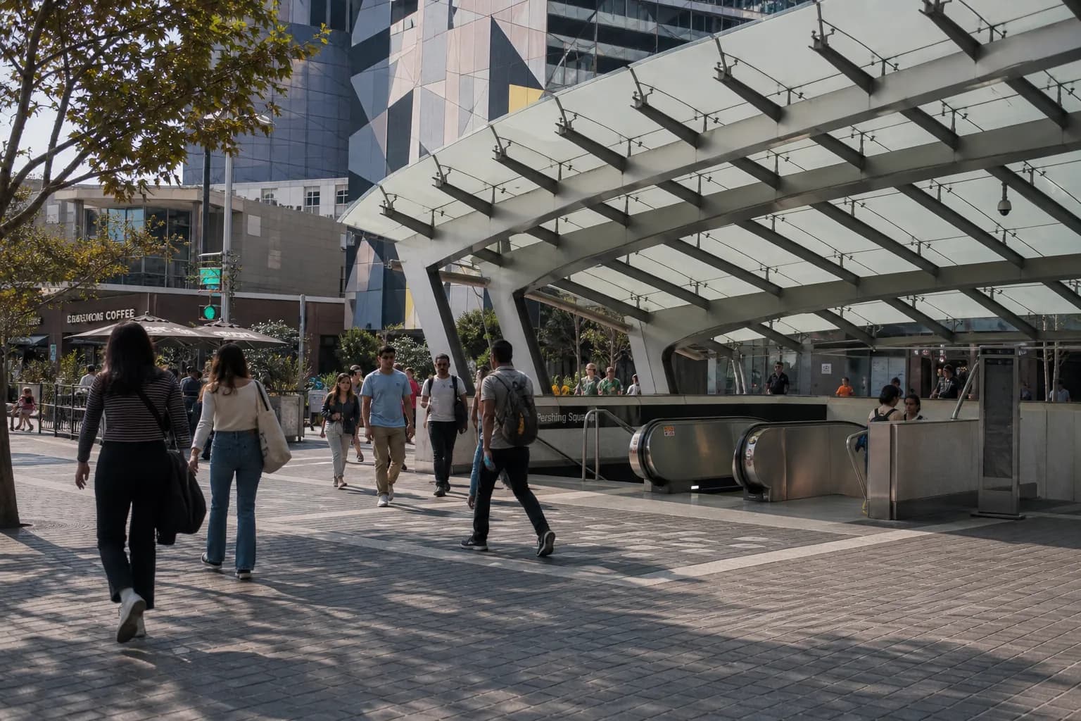 Urban commuters walking past the modern transit-accessible entrance of The Bloc in Downtown Los Angeles