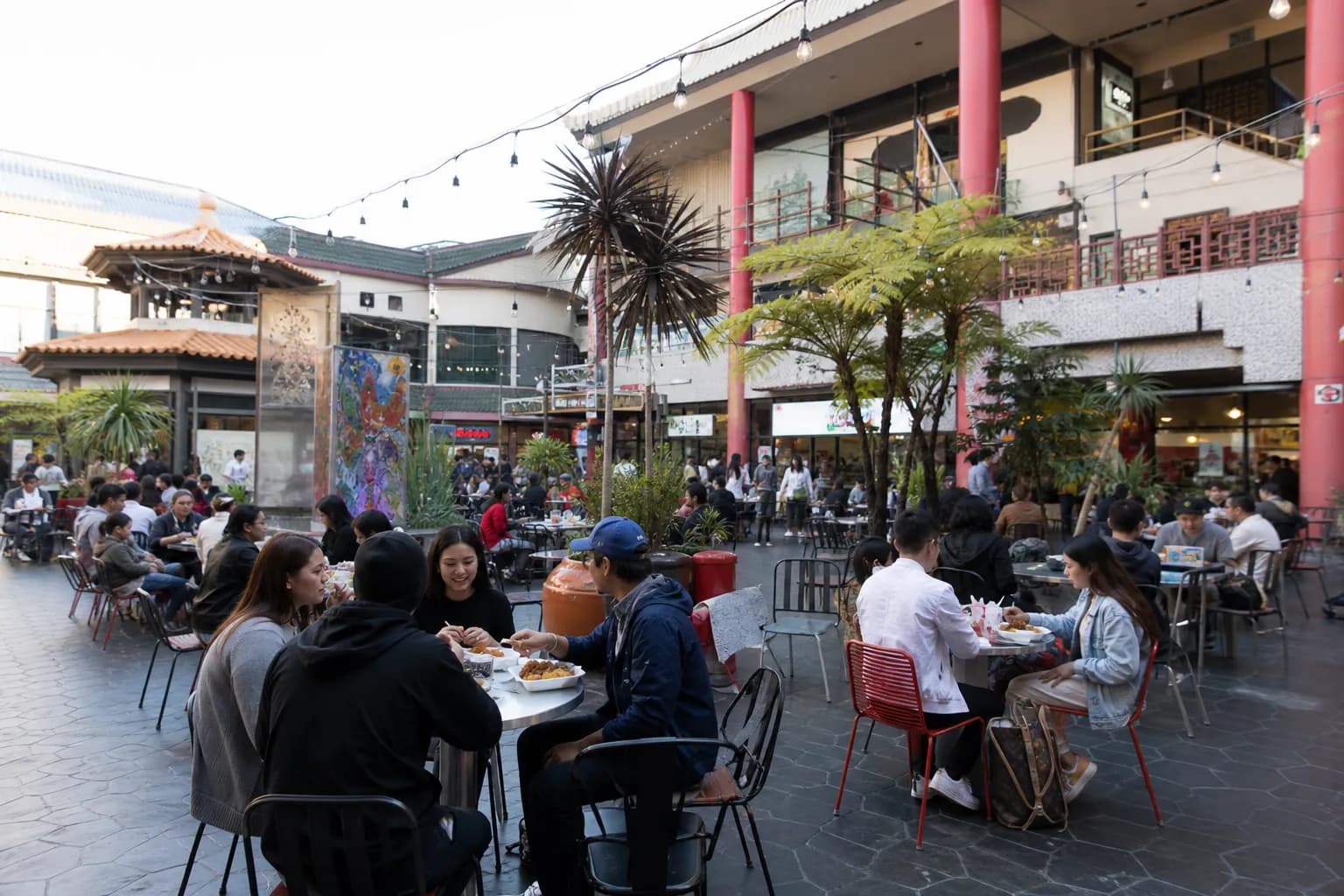 Wide shot of a bustling plaza in Downtown Los Angeles with people dining outdoors at local food stalls