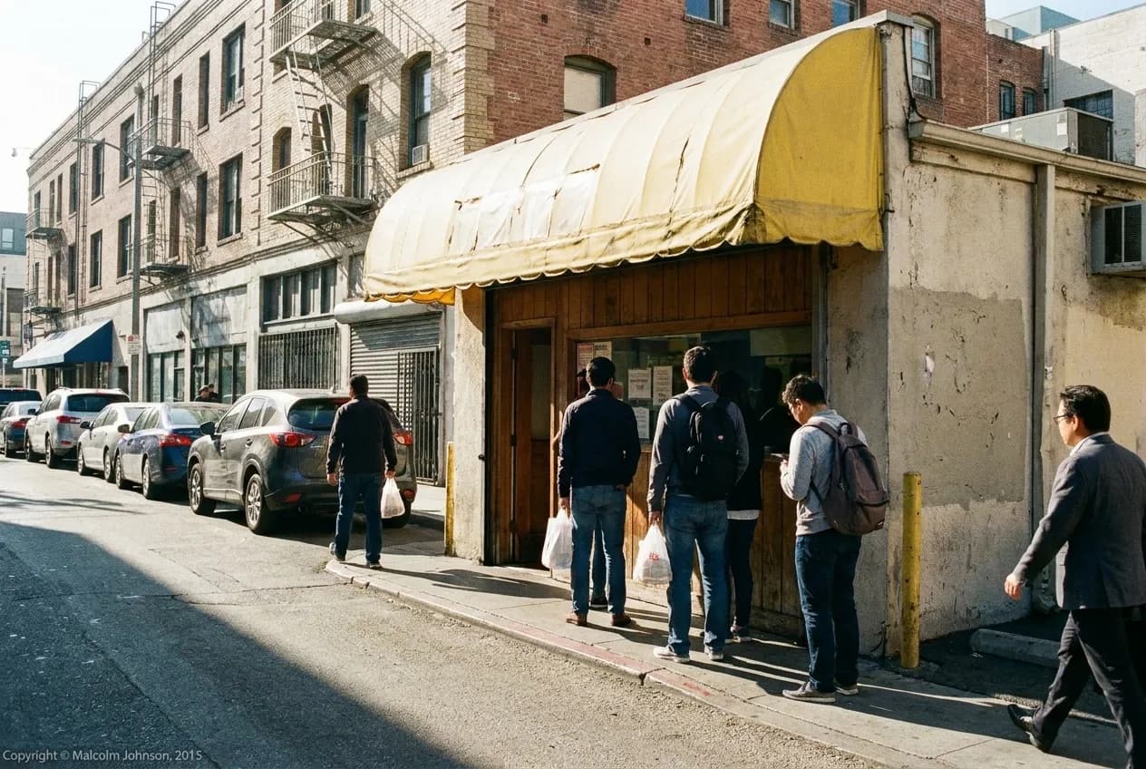 Pedestrians and a short queue outside a Little Tokyo ramen shop with yellow awning on 1st Street, Los Angeles.