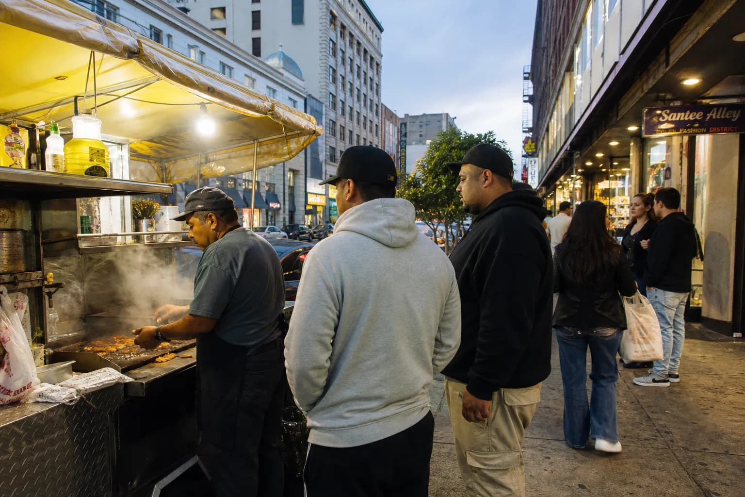Fashion District taco stand in Los Angeles with customers ordering on a busy early evening sidewalk