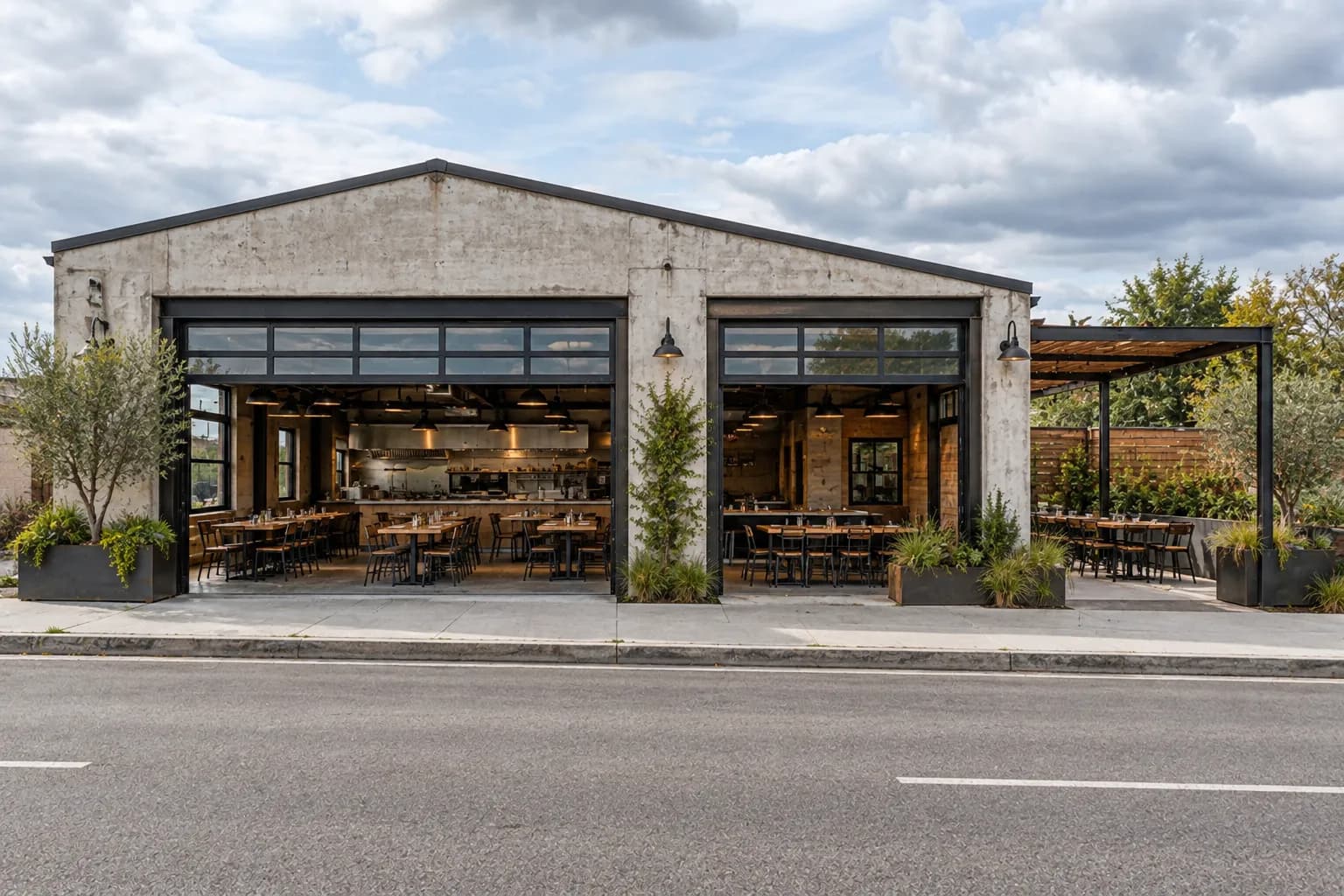 A broad restaurant frontage with open garage-style doors reveals an airy dining room, an open kitchen and a side patio, framed by pale concrete and dark metal.