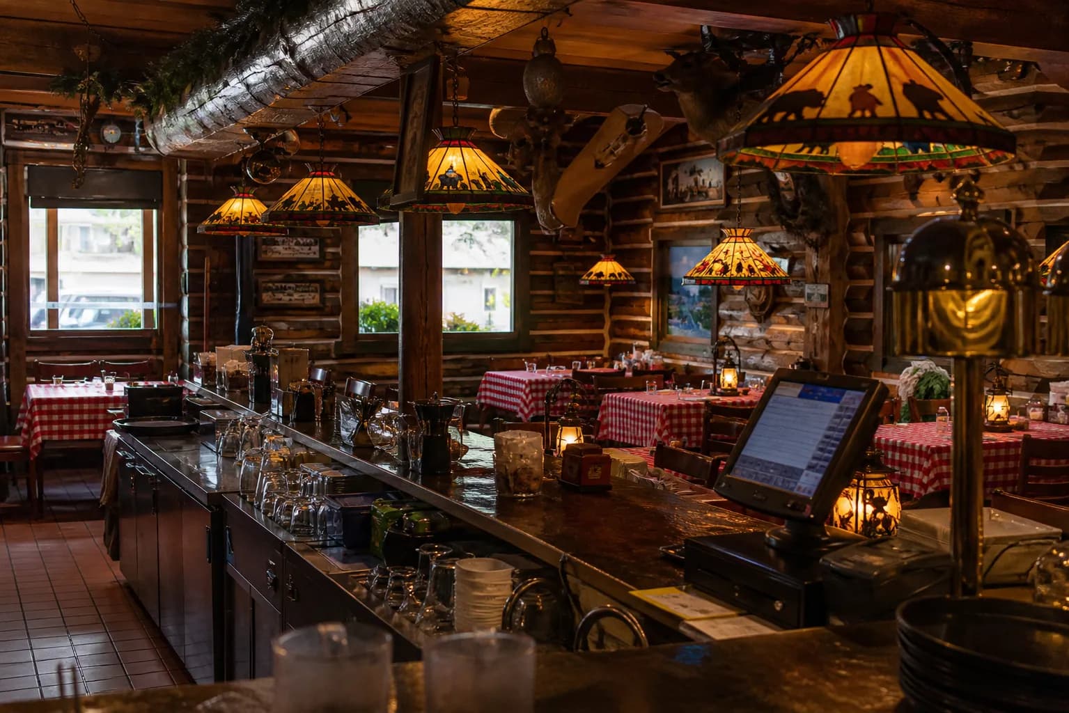 Cozy dimly lit booth interior of a classic wooden steakhouse with red leather seats and vintage lighting