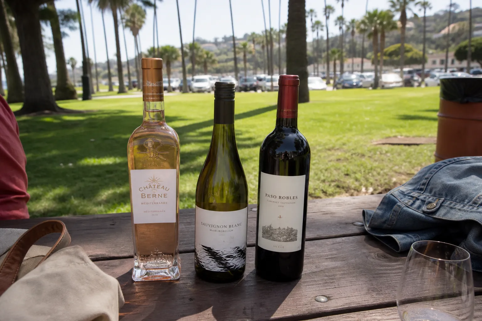 Three budget-friendly wine bottles resting on an outdoor picnic table in Los Angeles.