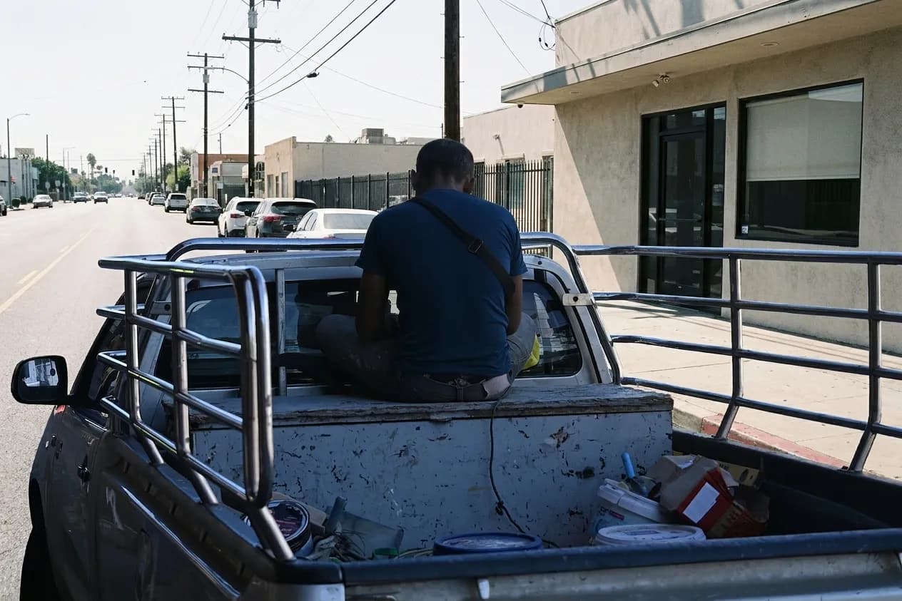 A plain single-storey Los Angeles storefront with a dark glass door and half-drawn blind under hard midday sun