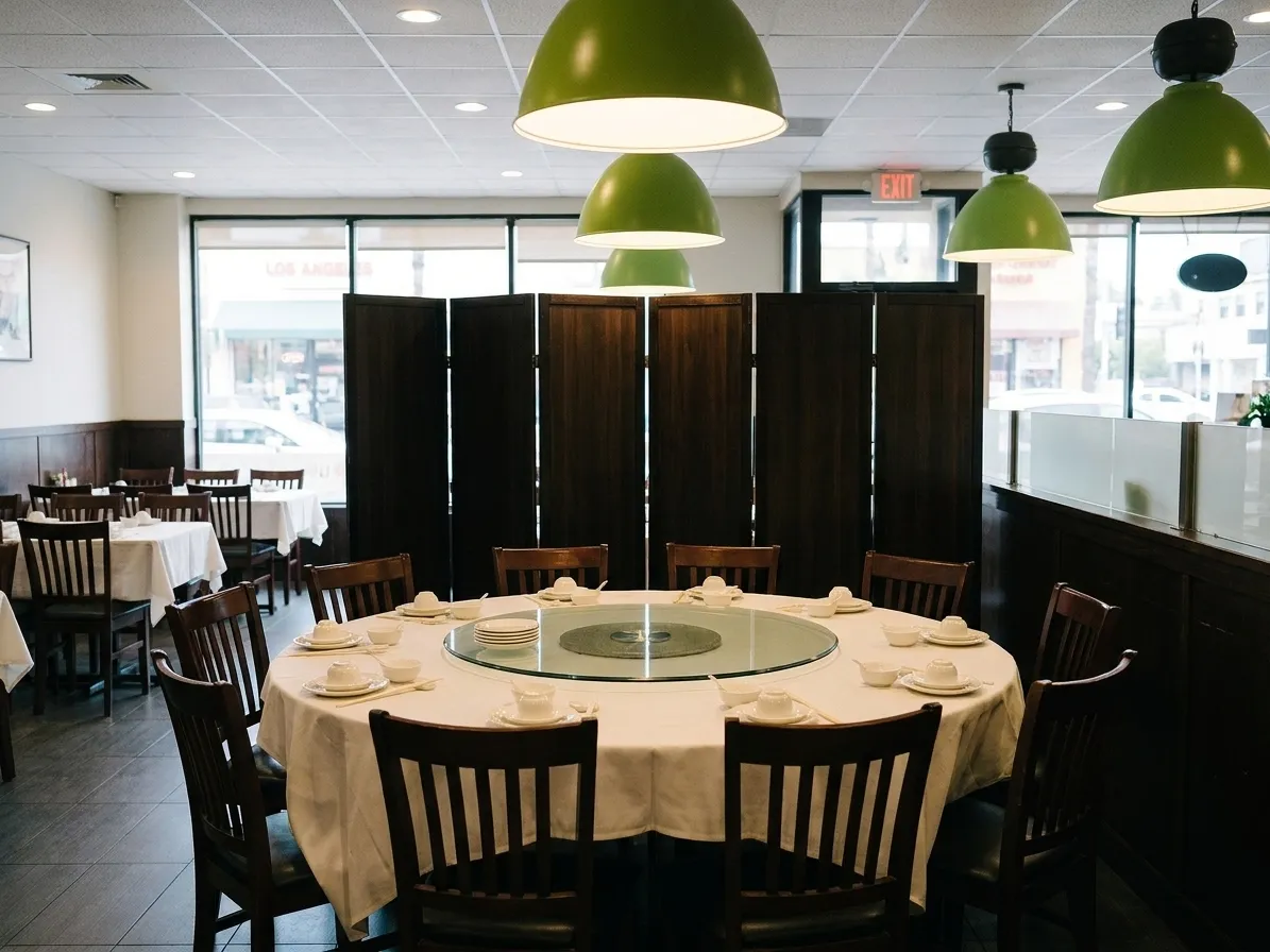 A large round banquet table with a glass lazy Susan and ten set places in a Los Angeles dining room, dark timber screens behind