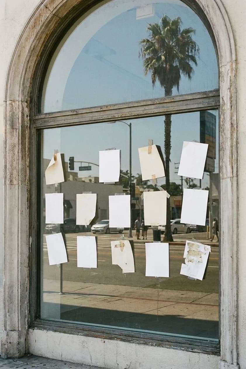A Los Angeles shopfront window used as a noticeboard, covered with blank paper flyers taped at different angles