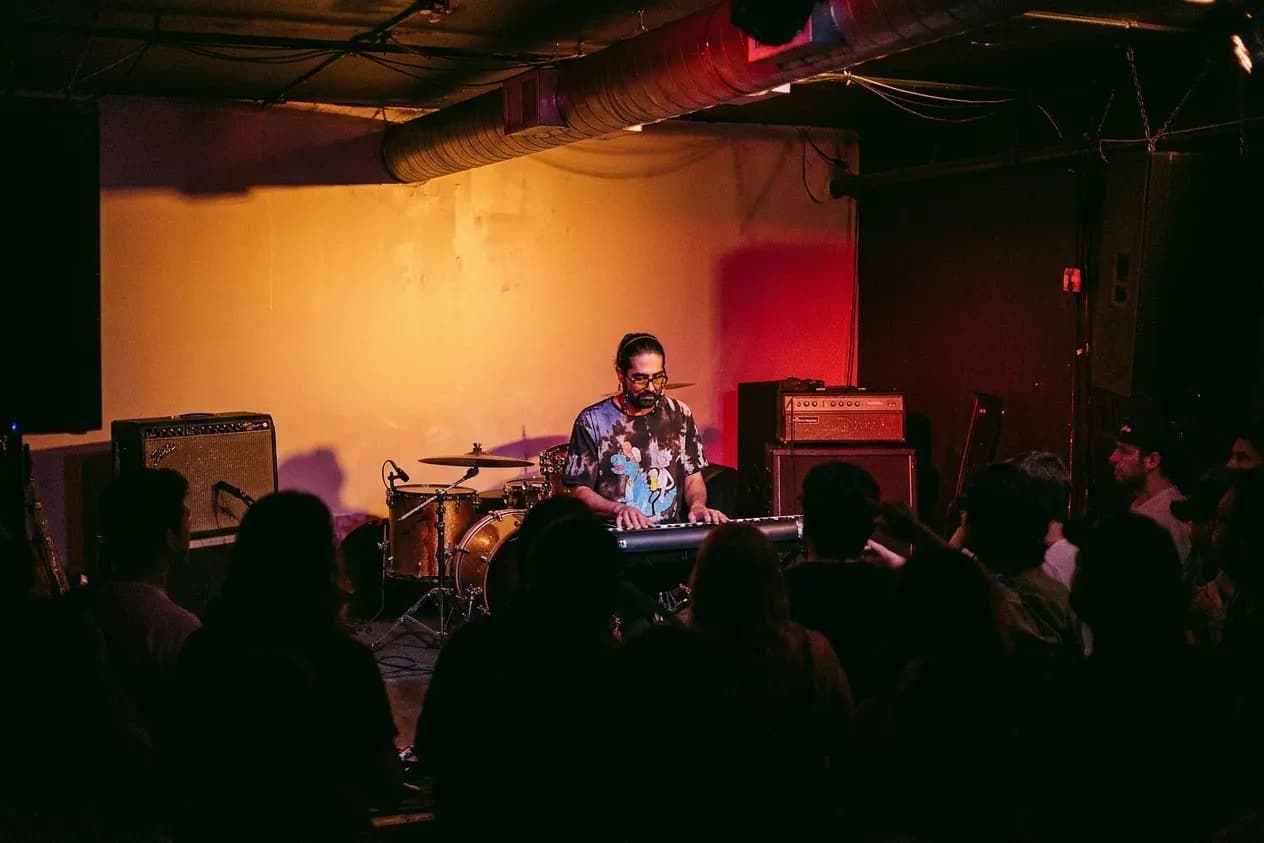 A small Los Angeles club with a barely raised stage, amber and red lighting and a crowd standing feet from the players