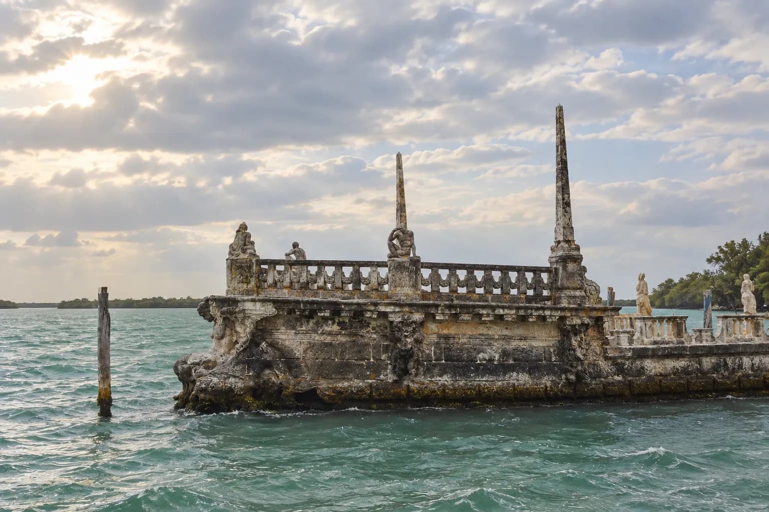 A carved stone breakwater sitting in shallow bay water