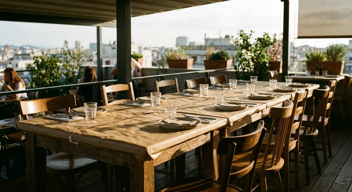 A long restaurant table pushed together for a party of ten with a paper-topped surface, water glasses and chairs pulled in at angles