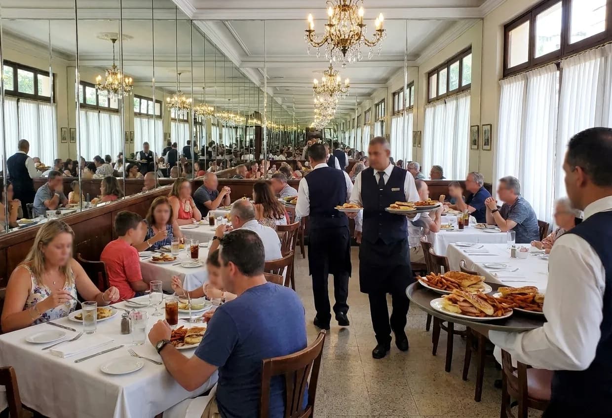 A large Cuban dining room at Sunday lunchtime with mirrored walls, chandeliers and white-clothed tables filled with families