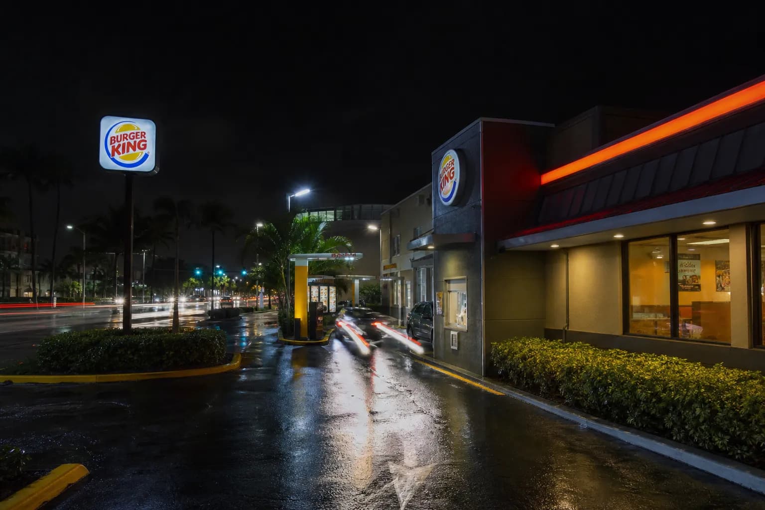 The bright outdoor drive-thru lane of a fast food restaurant in Miami Beach at night.