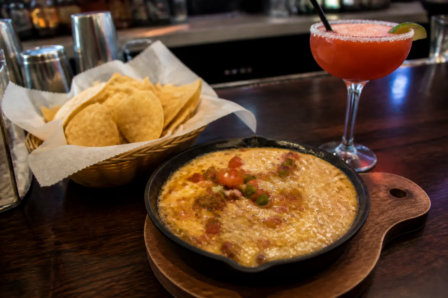 Chili's skillet queso and margarita on a wooden bar counter.