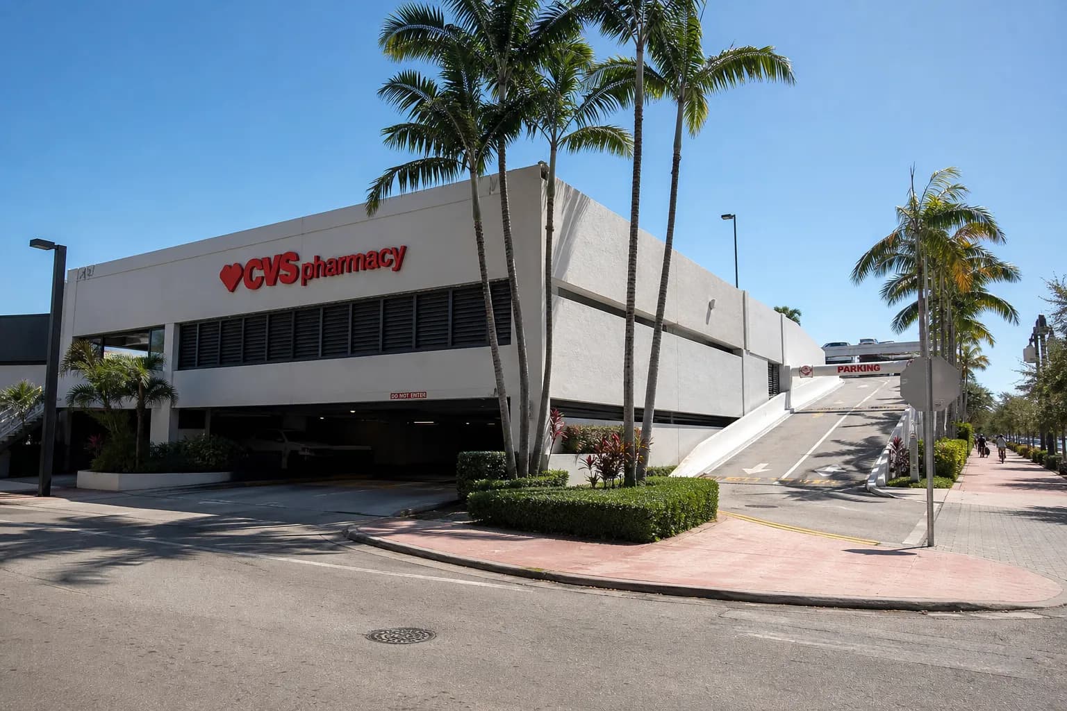 Exterior daytime view of the Alton Road CVS building with palm trees and the entrance to the rooftop parking deck.