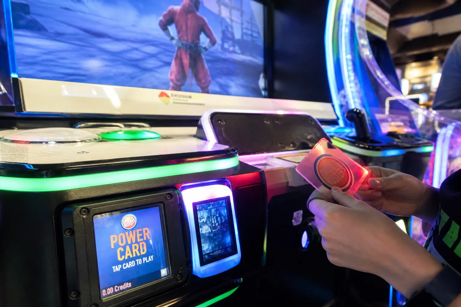 A player tapping a Power Card on a glowing arcade game console.