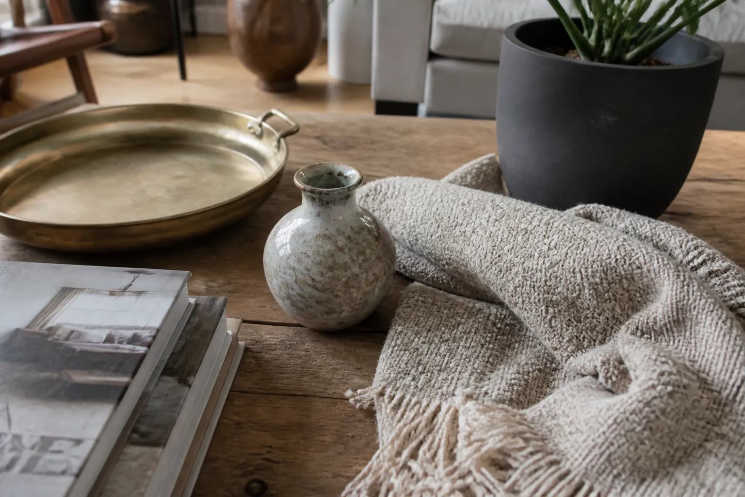 Close-up of minimalist home decor accessories including brass and ceramics on a wooden surface