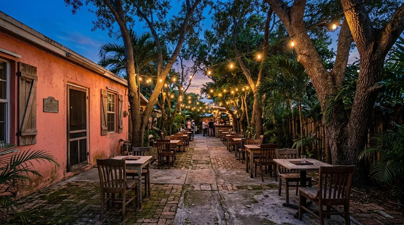Empty backyard at dusk with string lights over mismatched tables before the evening crowd