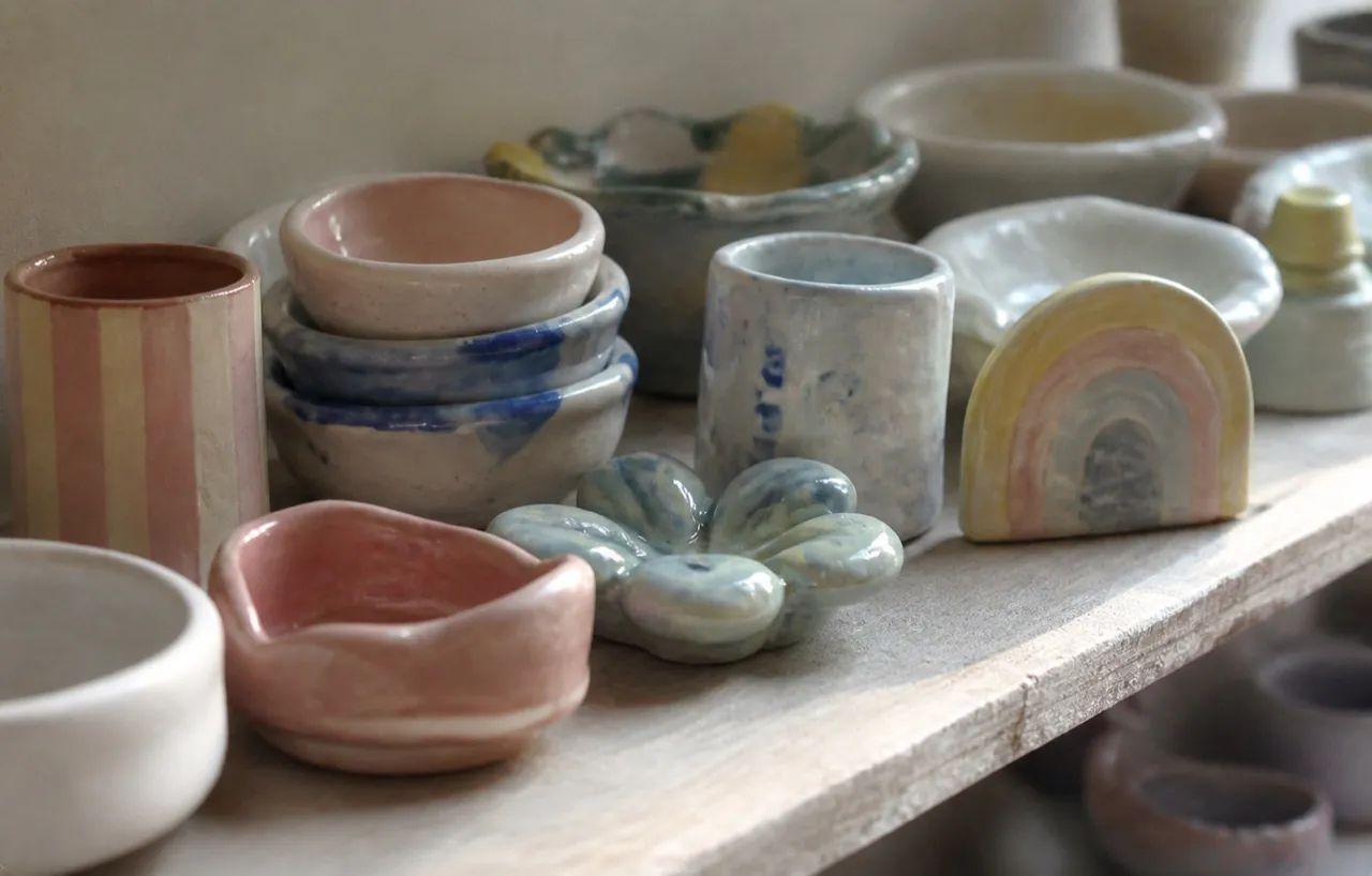 Painted ceramic pieces drying on a studio shelf